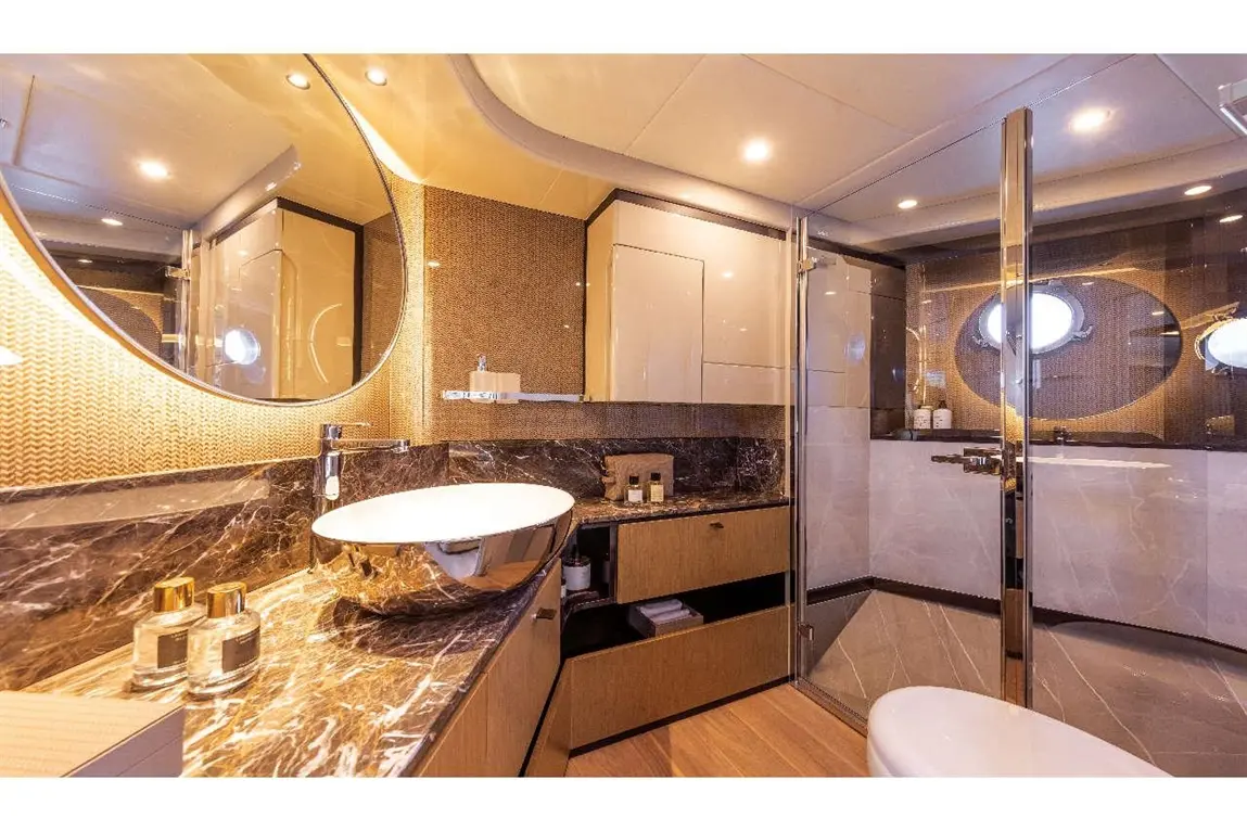 Luxurious bathroom featuring a marble countertop, modern sink, shower, and elegant decor with ambient lighting.